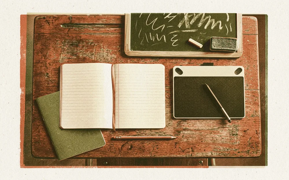 Overhead view of a classroom desk with notebooks, a digital tablet, chalk and pencil in warm earth tones