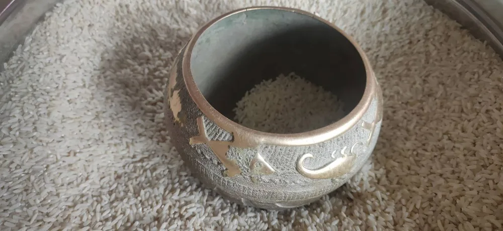 A paila, a metal kitchen utensil used to measure rice in Bihar, India, embossed with scorpion and fish patterns